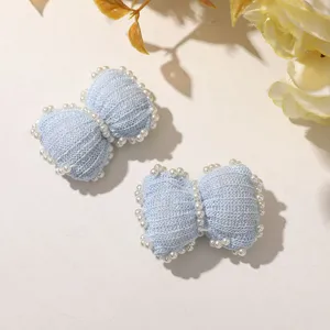 Detailed view of cute light blue yarn bow hair clips with white pearl edge decor, DIY accessories.