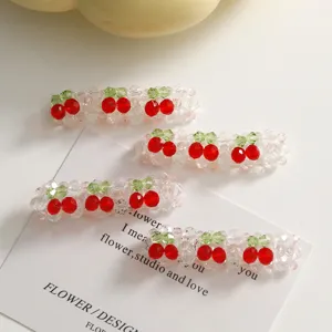 Gros plan de pinces à cheveux cerises en perles de cristal faites main au design scintillant.