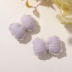 Close-up view of cute light purple knitted pearl bow hair clip detail showing texture and beads.