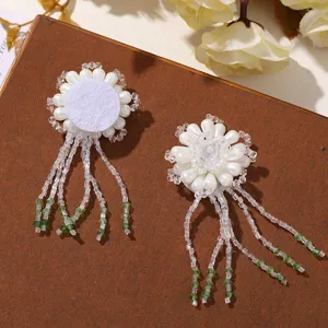 Gros plan détaillé d'un patch floral artisanal en perles avec des pompons pour le bricolage.