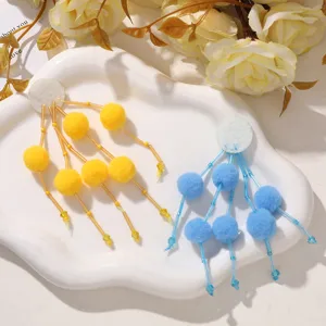 Primer plano detallado de lindos accesorios de pompones esponjosos hechos a mano en amarillo y azul.