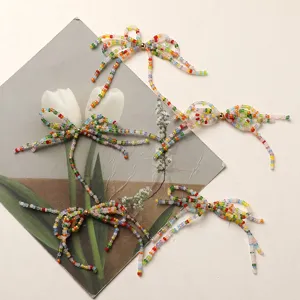Dettaglio accessorio fai da te con fiocco di perline colorate che mostra delicate nappe e lavorazione.