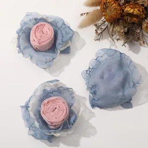 Detalle de flor de rosa de tela con borde quemado, ideal para manualidades DIY y decoración de ropa.