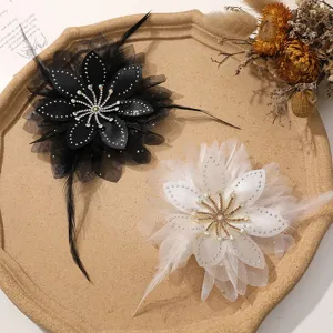 Dettaglio di spilla e fermaglio per capelli con fiore in piuma e strass di squisita fattura.
