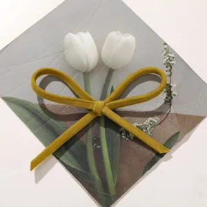 Dettaglio fiocco in velluto giallo senape, accessorio fai da te retro per vestiti e ciondolo borsa