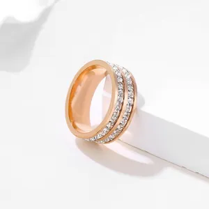 Close-up detail of double row rhinestone crystal stainless steel rose gold ring surface texture.
