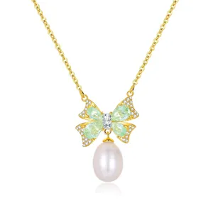 Detailed view of the mint green crystal bow pendant necklace with a dangling freshwater pearl.