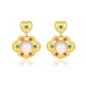 Close-up detail of retro gold-plated silver filigree earrings with pearl and stones.