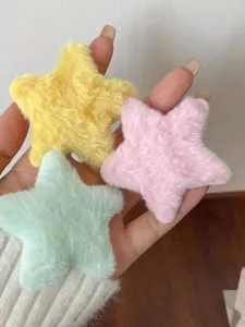 Detailed shot of cute plush star hair clips in yellow, pink and green, soft texture closeup.