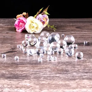 Clear crystal glass balls close up, small transparent glass beads scattered on wood