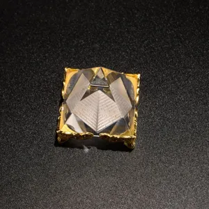 Crystal pyramid ornament detail shot, clear glass pyramid sculpture with ornate gold metal base.