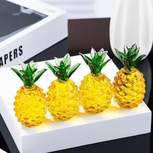 Primo piano di statuette di ananas in cristallo, ornamento da scrivania giallo trasparente.