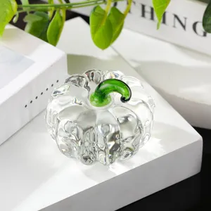 Close-up detail of clear crystal glass pumpkin figurine with green stem, elegant desk ornament.