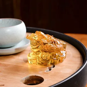 Detailansicht einer goldenen Feng-Shui Dreibeinige-Geldkröte Figur auf einem Holzteetablett.