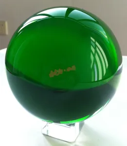 Detailed close-up of a green crystal ball with clear stand, elegant home decor item.