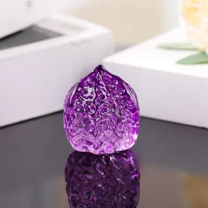 Purple glass walnut ornament close-up, smooth and translucent handheld art piece detail view.