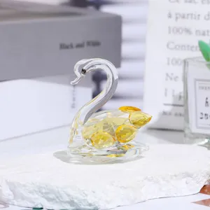 Crystal swan figurine featuring faceted yellow crystals displayed on a white stone base.