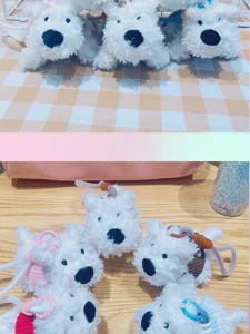 Dettaglio in primo piano di simpatici portachiavi a forma di cucciolo di terrier in peluche bianco.
