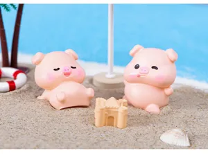 Detailed view of cute resin pig figurines in beach micro landscape for desktop decoration.