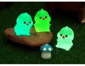 Figuras de resina de pollitos luminosos en miniatura, detalle de micropaisaje de jardín.