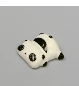 Vista detallada de un bonito soporte para palillos de panda de cerámica y decoración, negro y blanco.