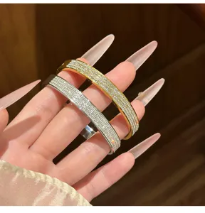 Close-up detail shot of dual-tone multi-row rhinestone paved steel bangles worn on hand.