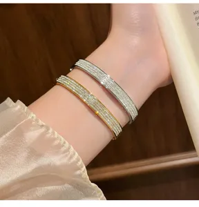 Close-up detail shot of dual-tone rhinestone paved titanium steel bangles worn on wrist.