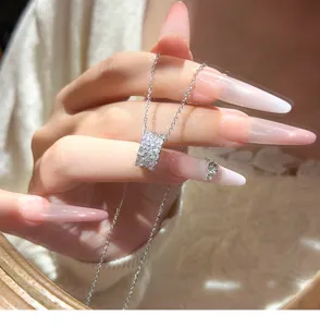 Close-up detail van een sprankelende strass cilinder hanger halsketting op hand.