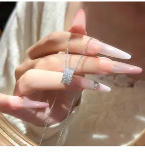 Detailopname van de sprankelende, met pavé bezette cilindrische hanger ketting aan fijne ketting.
