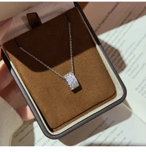 Gedetailleerde opname van een delicate zirconia cilinder hanger ketting in een bruine doos.
