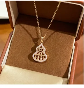 Closeup detail of the elegant gold gourd and abacus pendant necklace set with sparkling stones.