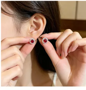 Close-up detail of luxury round red zircon halo stud earrings showcasing exquisite pave work.