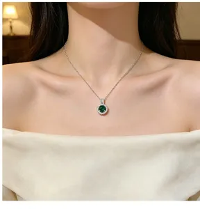 Close-up of an elegant silver clavicle chain necklace featuring a green stone pendant.