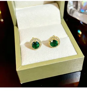 Detailed view of exquisite green zircon halo stud earrings featuring sparkling pave stones in box.
