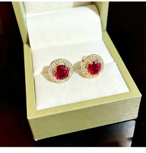 Close-up detail of luxury round red zircon stud earrings with sparkling halo diamonds.