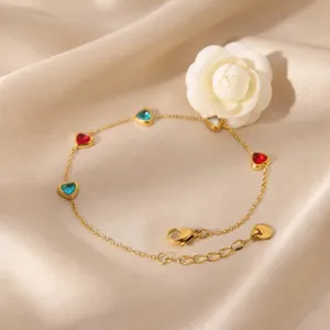 Stainless steel gold chain bracelet featuring colorful heart-shaped zirconia crystals. Detail view.