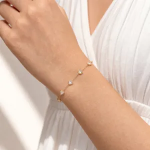 Close-up view of a delicate gold chain bracelet featuring sparkling heart-shaped clear stones.