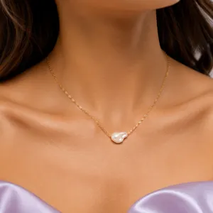 Exquisite detail of baroque pearl pendant necklace with delicate gold chain design, elegant wear.