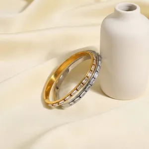 Stainless steel dual-tone bangle bracelet with sparkling baguette zirconia stones for women.