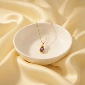 Gold teardrop pendant necklace detail shot, purple zircon stone, elegant jewelry display.