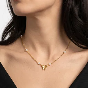 Primo piano della collana con farfalla placcata in oro e perle indossata al collo.