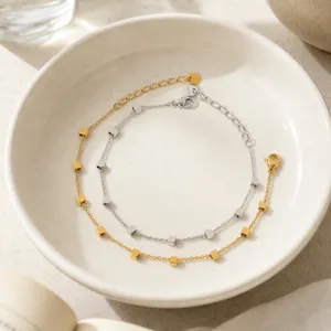Primer plano detallado de pulseras geométricas minimalistas con cubos en oro y plata.