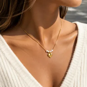 Detail shot of minimalist gold heart pendant necklace with freshwater pearls and steel chain.
