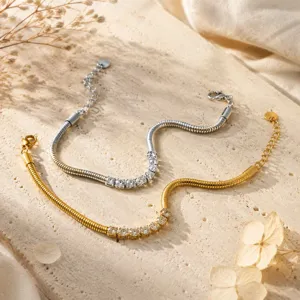 Primer plano de elegantes pulseras de cadena serpiente con pedrería en oro y plata chic.