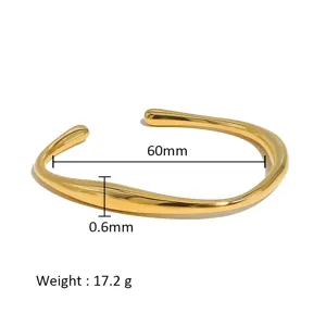 Vista detallada de pulsera brazalete abierto de acero inoxidable dorado con diseno irregular.