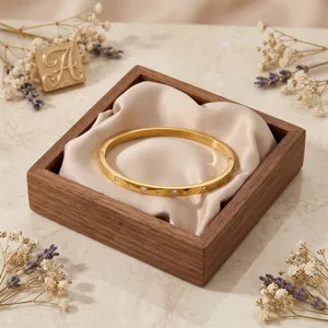 Brazalete rígido de acero inoxidable dorado con piedras de cristal brillante en caja.