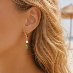 Detailed shot of gold-plated hoop earrings featuring a freshwater pearl and a green zircon pendant.