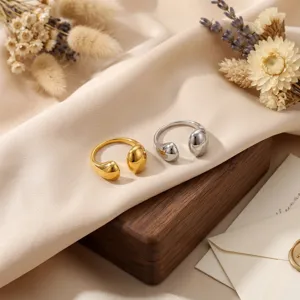 Primer plano detallado de anillos abiertos dorados y plateados con diseño de gota único.