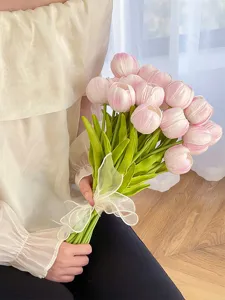 Vista detallada de un ramo de tulipanes rosas artificiales con tallos verdes y lazo.