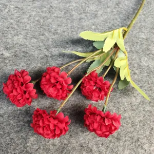 Gros plan détail de fleur de chrysanthème artificielle rouge avec des tiges et des feuilles.